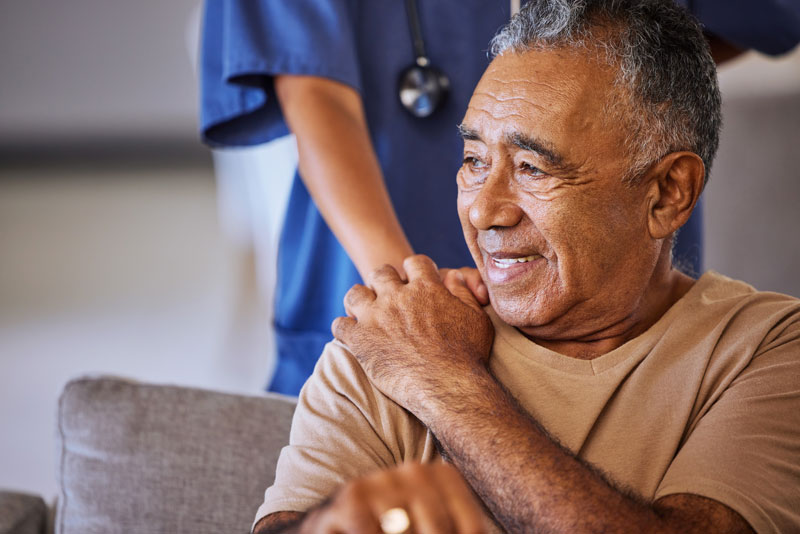 Elderly man smiling, holding the hand of nurse