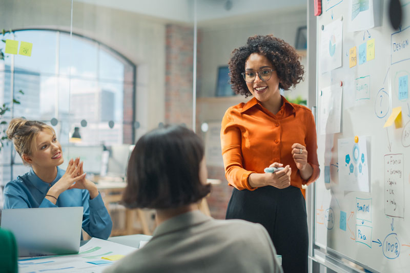 Woman presenting in front of two female colleagues