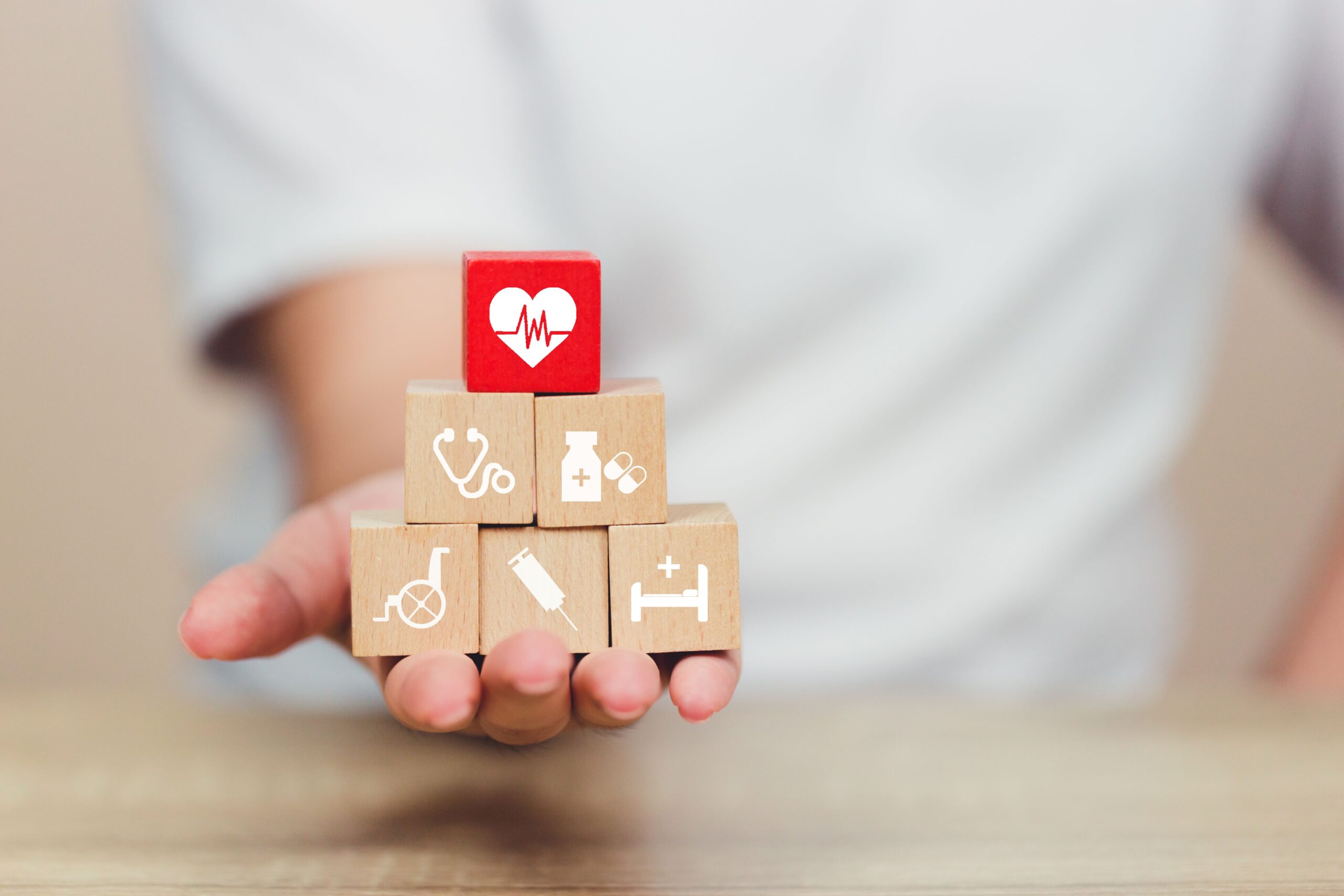 Person holding blocks with various health and care icons