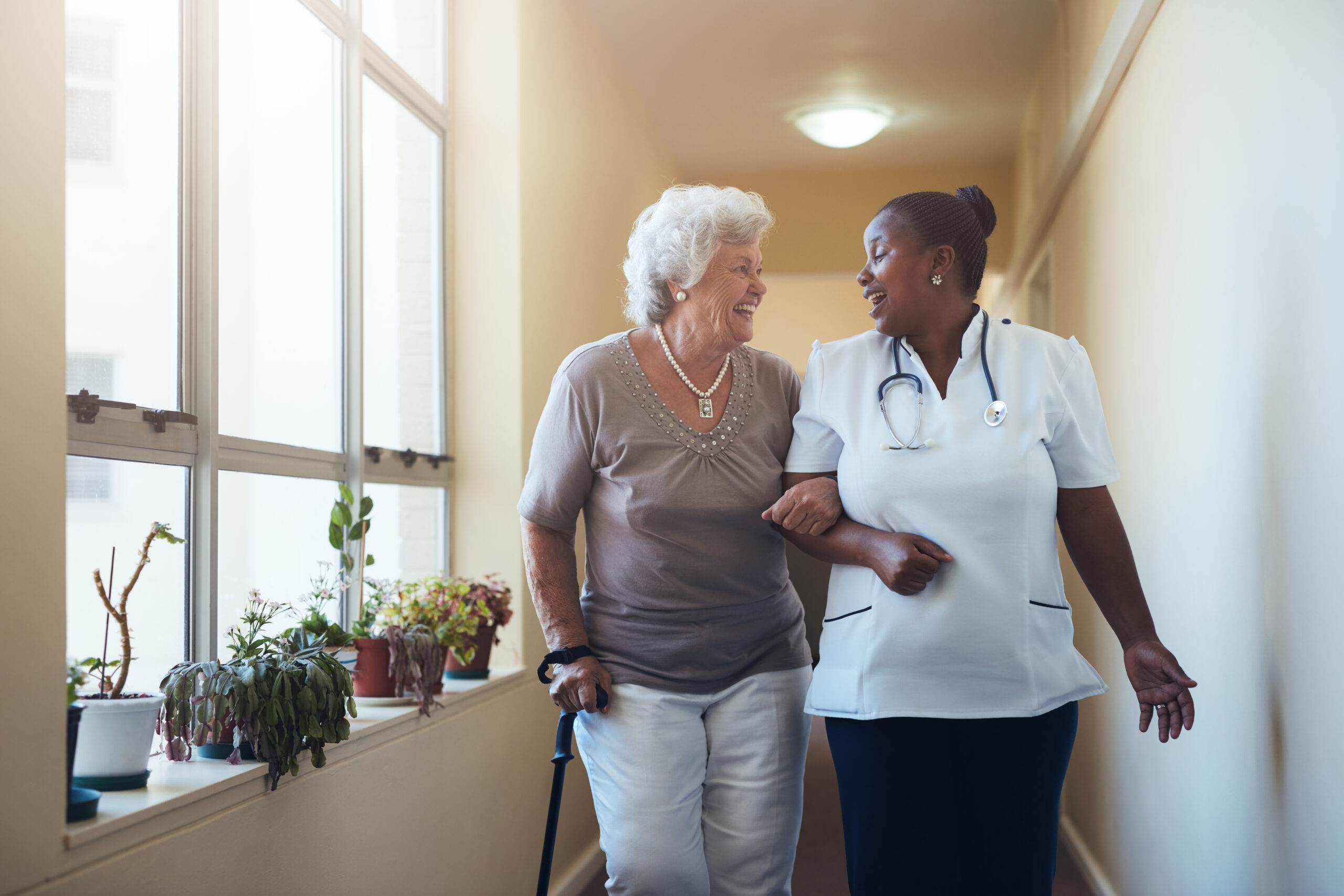 Nurse and elderly patient in care home corridor