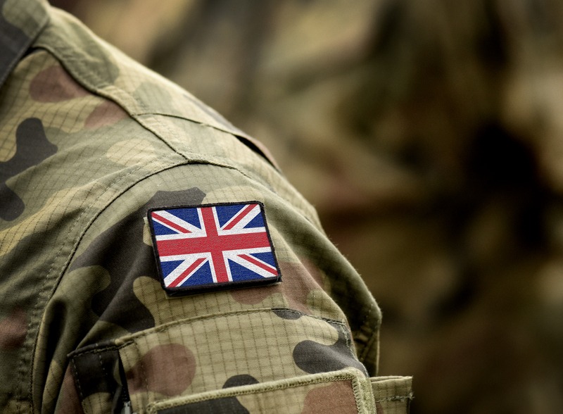 The shoulder of a person wearing army camouflage uniform with a union jack patch at the top of shoulder
