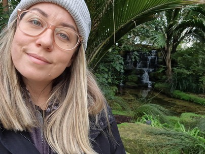 Chelsea smiling to camera with a forest and waterfall in the background