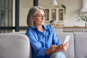 A lady sat on a sofa looking at her mobile phone